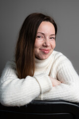 Vertical portrait of a laughing woman in warm white sweater. Cheerful happy 35 years old lady on grey close up
