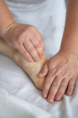 Fototapeta na wymiar Close-up of man doing foot massage on white background. Reflexology foot massage. Tired feet concept. Vertical