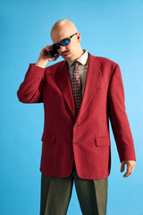 Portrait of balded man with mustache, dressed in vintage style standing and talking on retro phone...