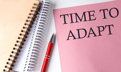 TIME TO ADAPT word on the pink paper with office tools on white background