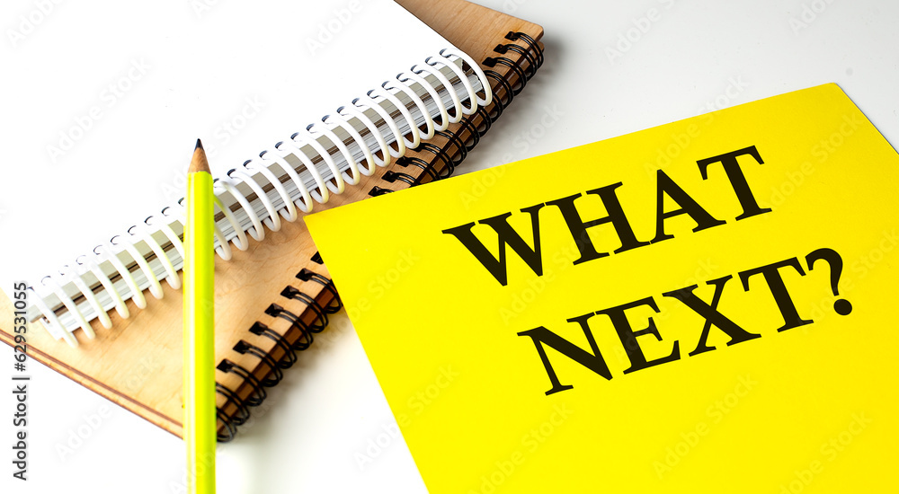 Poster what's next text written on a yellow paper with notebook