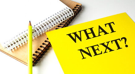WHAT'S NEXT text written on a yellow paper with notebook