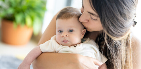 Mother kissing her infant baby home.