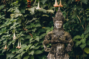 Close up shot of balinese statue with green leaves background. Traditional indonesian architecture and religious sculpture