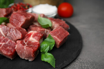 Cut fresh beef meat and basil leaves on brown table, closeup. Space for text