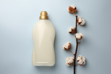 Bottle of fabric softener and branch with fluffy cotton flowers on light background, flat lay