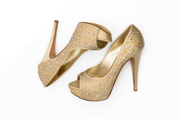 Shiny golden shoes with high-heeled stones on a white background