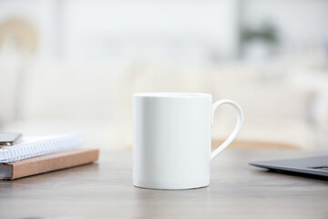 White ceramic mug and notebooks on wooden table indoors. Space for text