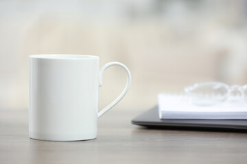 White ceramic mug on wooden table indoors. Space for text