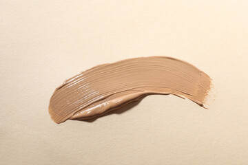 Swatch of skin foundation on beige background, top view