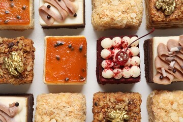 Pieces of different delicious cakes on white table, flat lay