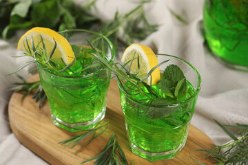 Glasses of refreshing tarragon drink with lemon slices on tablecloth