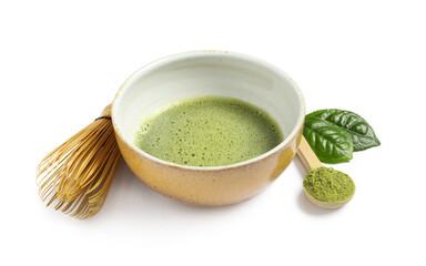 Cup of fresh matcha tea, spoon with green powder and bamboo whisk isolated on white
