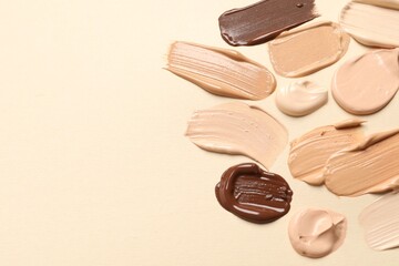 Samples of skin foundation on beige background, flat lay. Space for text