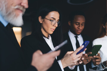 Focused diverse colleagues using smartphones in office