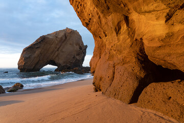 Santa Cruz beach with its famous natural arch formation at sunset, Portugal.