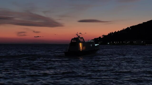 Motor speed boat going to island shore against colorful sunset sky