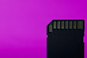 Close up of a used SD card straight on with purple backrop.
