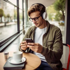 Photo sur Plexiglas Magasin de musique Smiling Man looking at phone at coffee shop, browsing mobile apps, reading news, chatting or shopping online, holding smartphone. Man in casual clothes with cup coffee