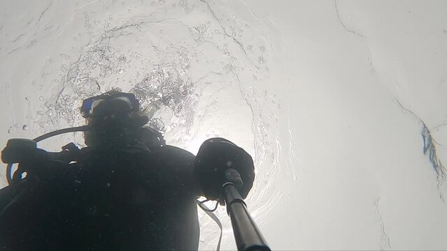 Camera looking up at scuba diver silhouetted against bright sun from above underwater video. Colombia, Caribbean sea, Tayrona National Park.