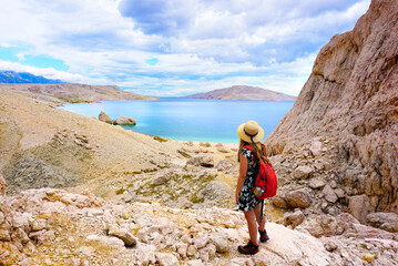 Obraz premium Free carefree joyful girl traveler standing on hill rock over sea bay in Croatia, Europe. Watching over beach Beritnica. Enjoy travel concept 