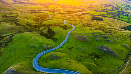 Aerial view of green volcanic landscape with mountain road. Curvy Mountain Road Sunset. 
