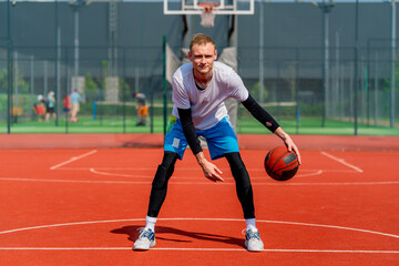 Obraz premium a Tall guy basketball player with the ball shows his dribbling skills during practice on the basketball court in the park 