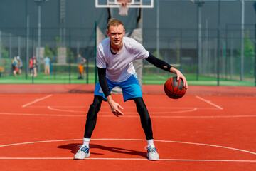 a Tall guy basketball player with the ball shows his dribbling skills during practice on the basketball court in the park 