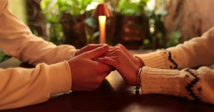 Close-up of the hands of a couple in love sitting at a table in a cafe on a romantic date. Male and female hands interacting with each other at the moment of a romantic meeting of a couple in love.