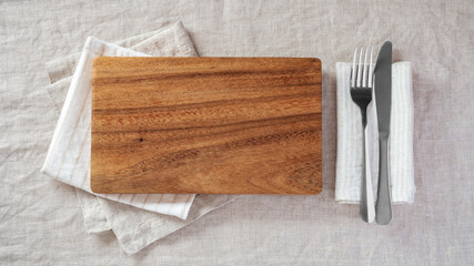 Wood plate with fork and knife on napkin on linen tablecloth