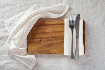 Wood plate with fork, knife and napkin on linen tablecloth