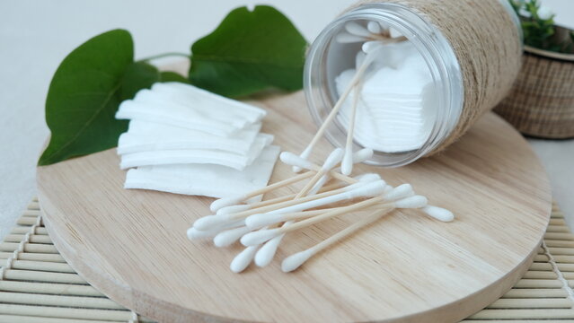 Close-up cotton pads and sticks lie on the table near the jar