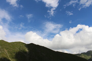 Obraz na płótnie Canvas A blue sky with clouds and a green hill