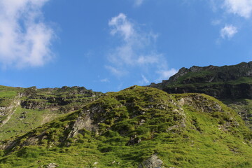 A green mountain with blue sky and clouds