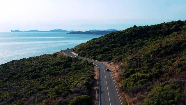 Car driving on a road next to the sea - Drone view - Sardinia