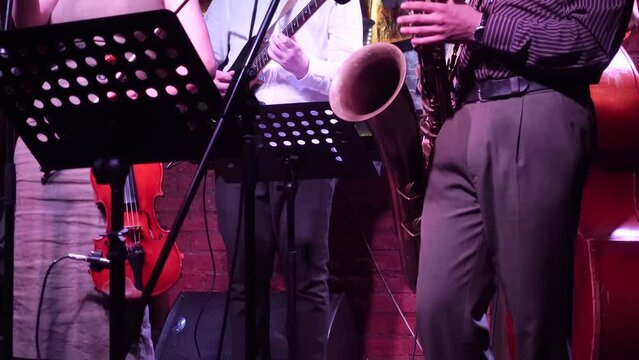 jazz band with saxophonist, guitarist and violinist gives a live concert on stage.