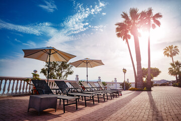 Sun loungers beach umbrellas and pool in sunset light