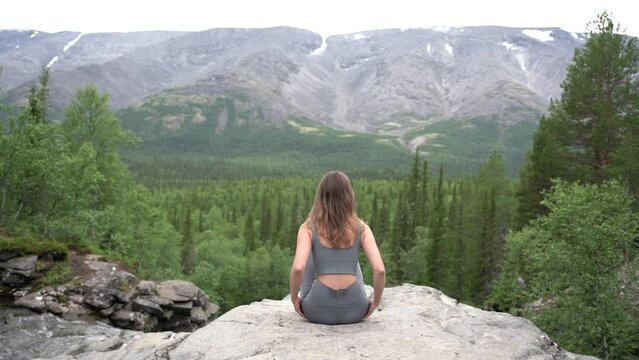 Meditation and harmony, a female coach does yoga exercise pose asana against the backdrop of mountains and nature of the north.