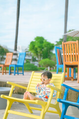 A boy sitting on a beach chair eating ice cream.