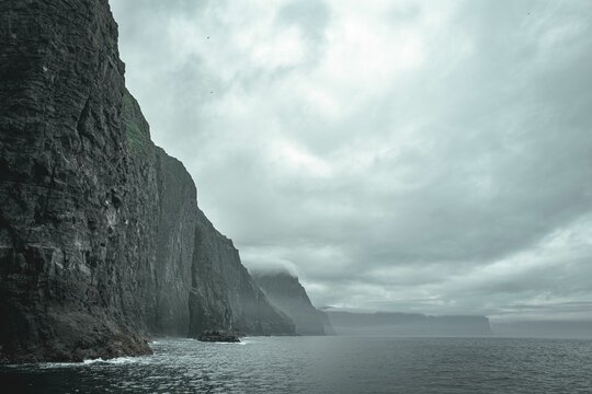 Scenic view of the rugged, natural landscape of the Faroe Islands with lush hills and fluffy clouds