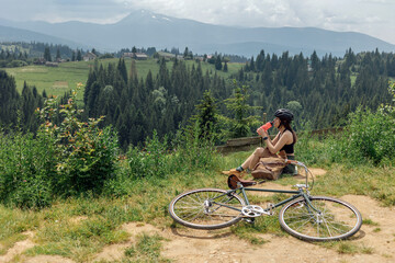 Obraz premium Young woman cyclist enjoy the beautiful view on green mountains trail
