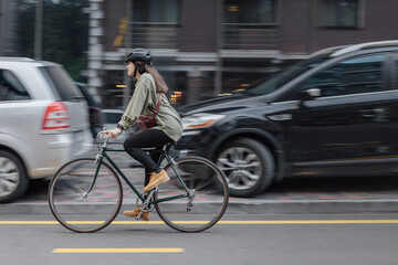 Woman rides bicycle fast in the city with blurred in motion background