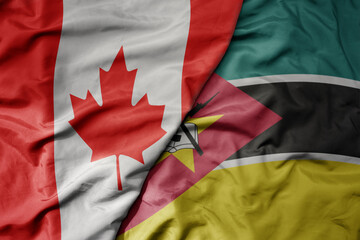 big waving realistic national colorful flag of canada and national flag of mozambique .