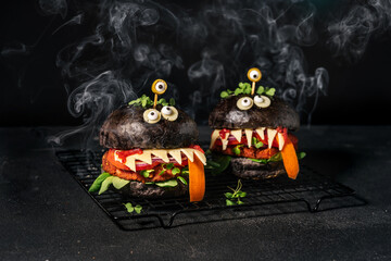 Monster sandwiches with black bun, vegan patty, cheese, olive eyes and smoke on the black...