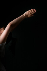 Femme en posture de Yoga sur fond noir, bras tendus