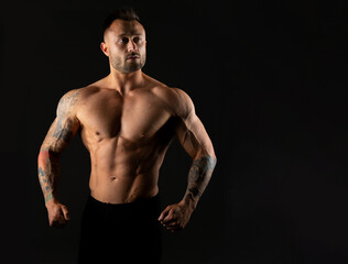 Fototapeta na wymiar Strong muscular man on a black background, studio photo. Bodybuilding, torso muscles.