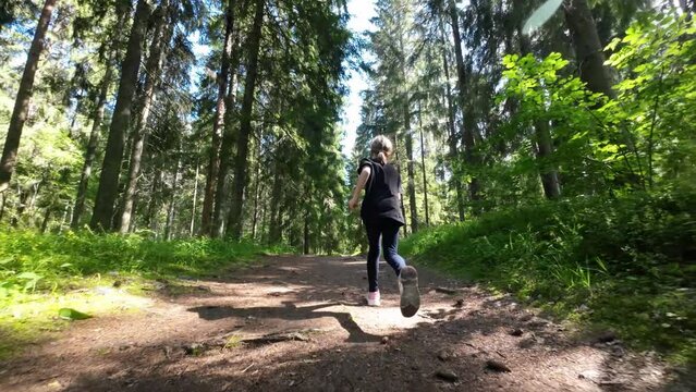 Little girl runs along a forest path in summer. Slow motion