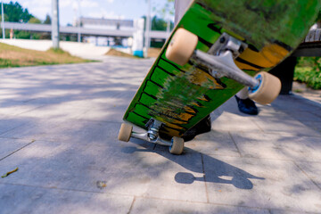 Close-up of a young boy doing a skateboarding trick on the path of a city park against the background of trees © Guys Who Shoot