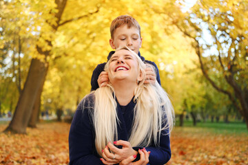 Mother and son spend time together in the autumn park, play and have fun. son tickles mother