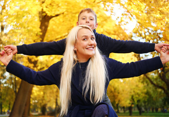Mother and son spend time together in autumn park, play and have fun